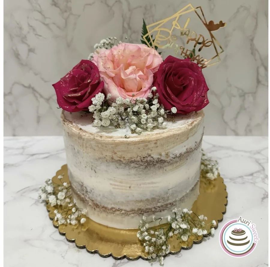 White semi-naked birthday cake topped with pink and burgundy roses