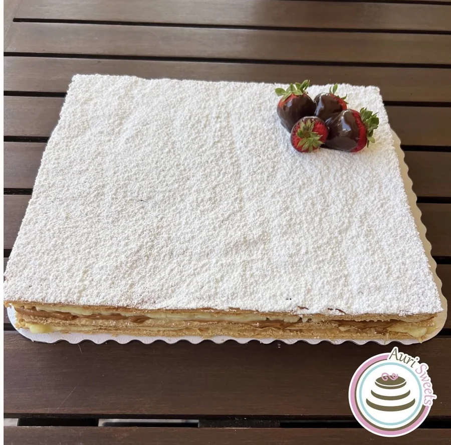 Rectangular layered pastry topped with powdered sugar and chocolate-dipped strawberries